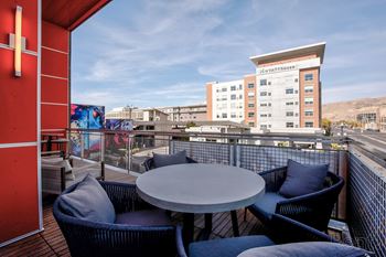 A patio with a table and chairs overlooking a building.